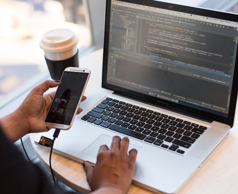 Person Holding Smartphone while using Laptop